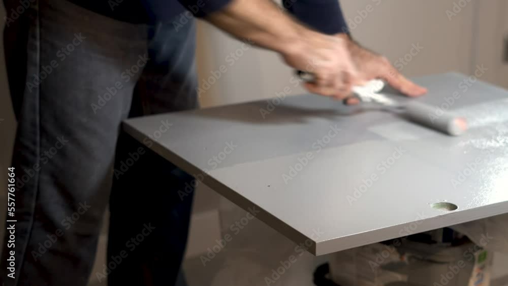 Man painting a piece of wood with a roller. Man painting a piece of wood with a roller.