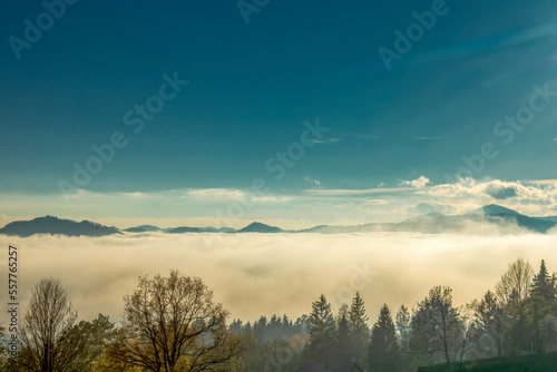 Heavy fog and mist surrounds forested mountain peaks