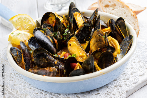 Traditional Italian sailors mussel in white wine sauce with vegetables and saffron served as close-up in a design frying pan
