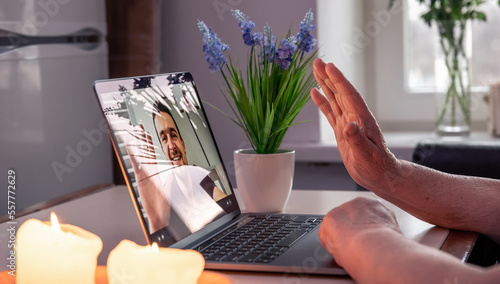 An old woman communicates with her son via video link through a laptop.