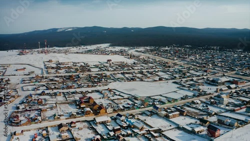 Flying over the houses of the huzhir village on Olkhon, the shore of Lake Baikal. Baikal, Siberia, Russia. A winter Siberian countryside landscape. Drone aerial shot