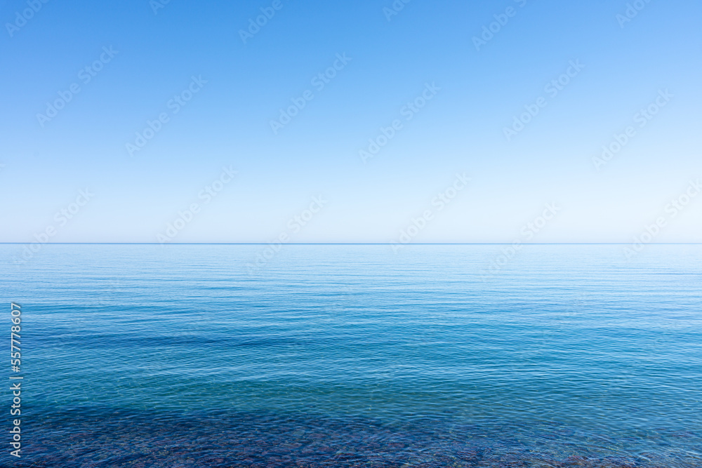 Ocean sky horizon line blends into infinity with blue turquoise colors of ocean waters and cloudless sky