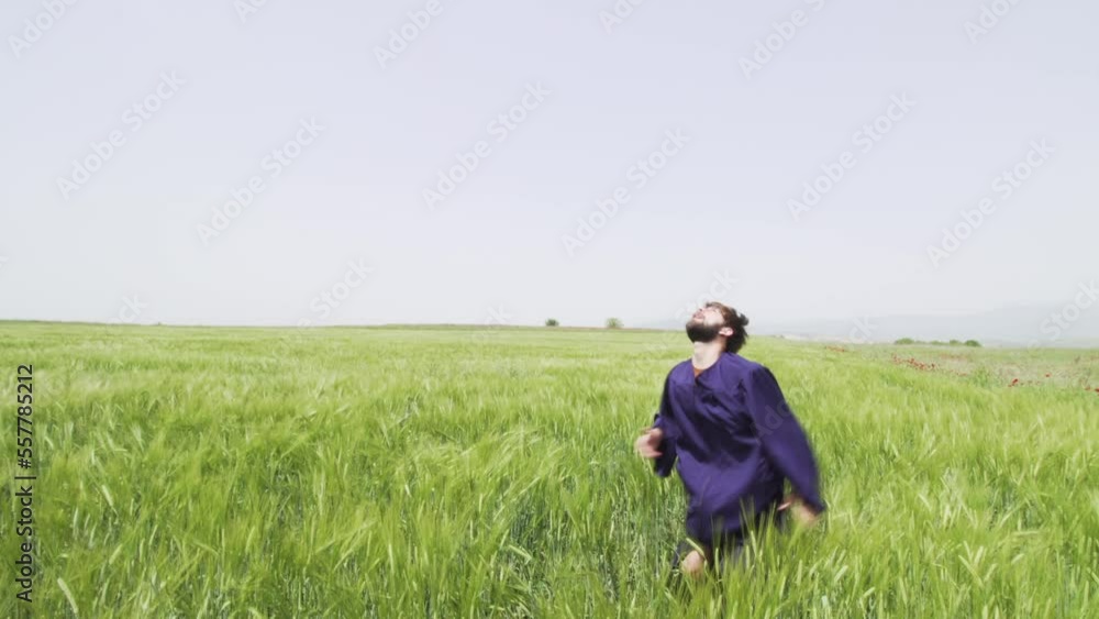 Young man with graduation clothes in a green field throwing hat in the air.. Young man with graduation clothes in a green field throwing hat in the air..