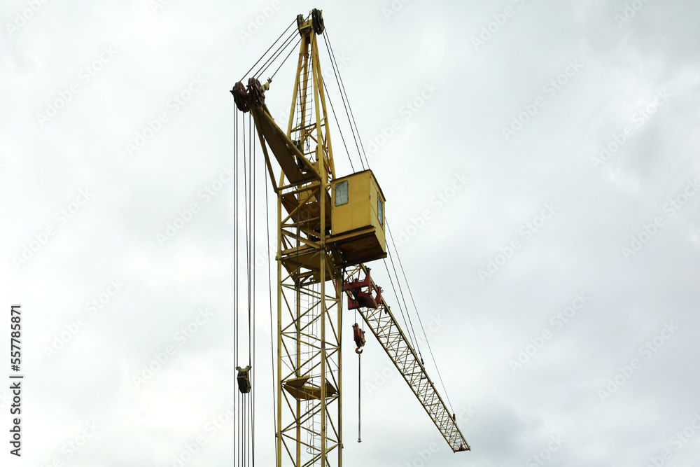 Construction site with tower crane under beautiful cloudy sky, low angle view