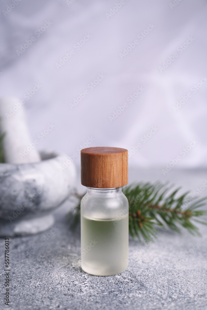 Bottle of aromatic essential oil and mortar with pine branch on light grey table, closeup. Space for text Bottle of aromatic essential oil and mortar with pine branch on light grey table, closeup. Space for text