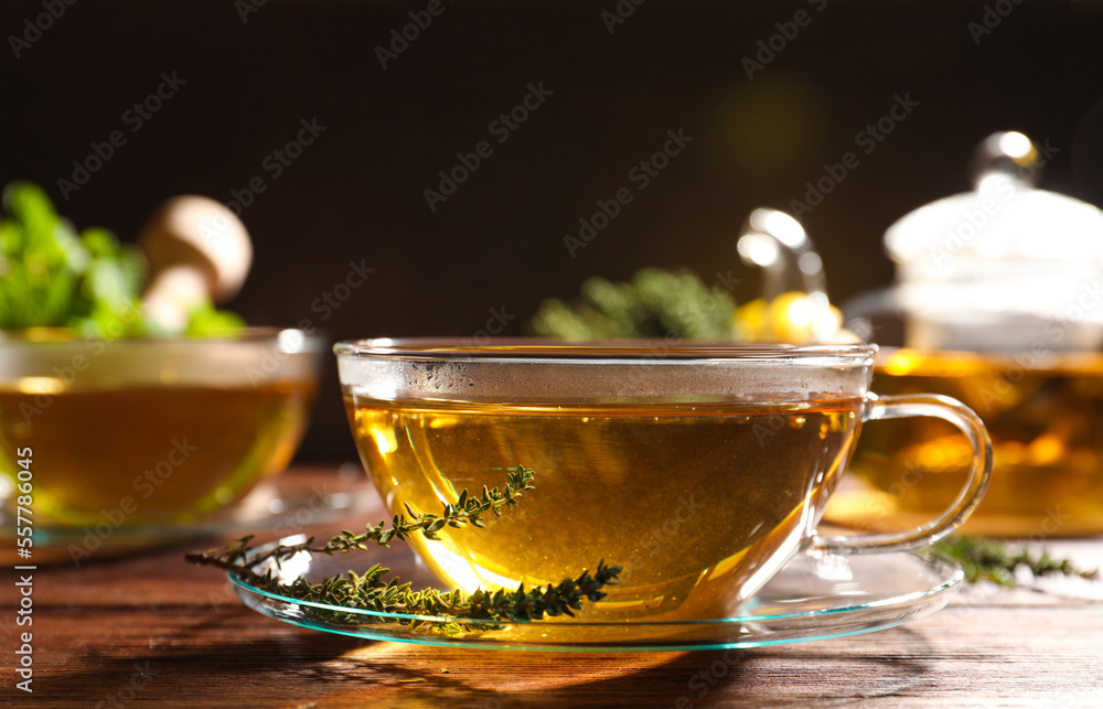 Cup of aromatic herbal tea and fresh thyme on wooden table Cup of aromatic herbal tea and fresh thyme on wooden table