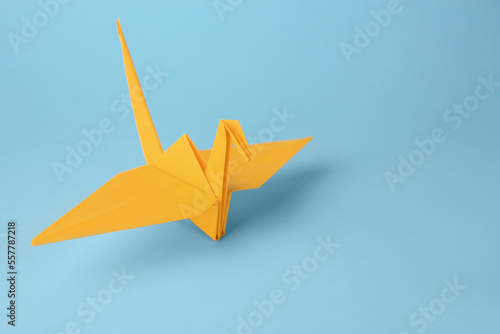 Origami art. Handmade paper crane on light blue background, space for text