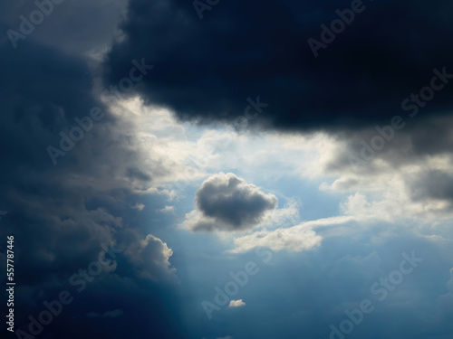 Low angle view of cloudy sky with ray of light coming through the dark rainy stormy clouds