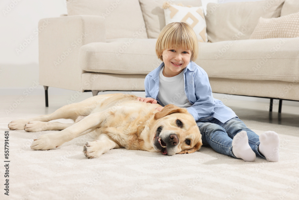 Cute little child with Golden Retriever on floor at home. Adorable pet