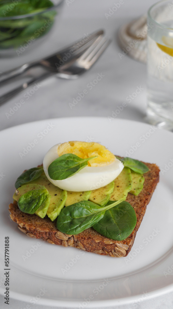 Tasty sandwich with boiled egg, avocado and spinach on white marble table, closeup Tasty sandwich with boiled egg, avocado and spinach on white marble table, closeup
