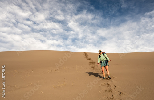 Woman Cautiously Hikes Down Steep Dune