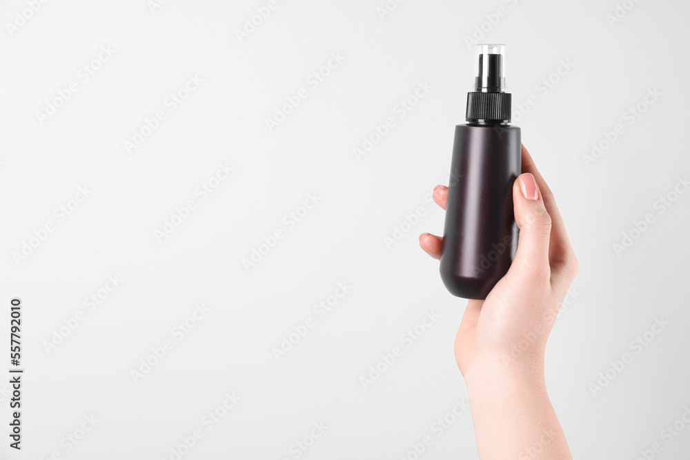 Woman holding spray bottle with hair thermal protection on white background, closeup. Space for text Woman holding spray bottle with hair thermal protection on white background, closeup. Space for text