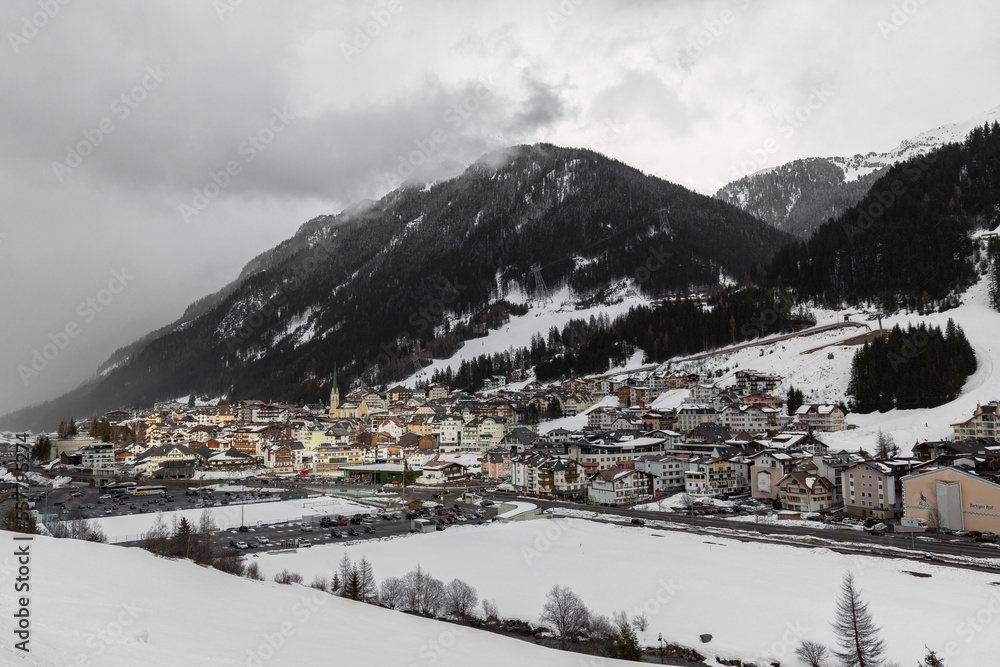 Ischgl ski resort village in Austria at bottom of mountain hills covered in snow with cloudy sky