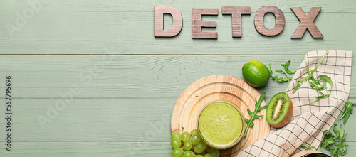 Glass of healthy smoothie with ingredients and word DETOX on green wooden background with space for text