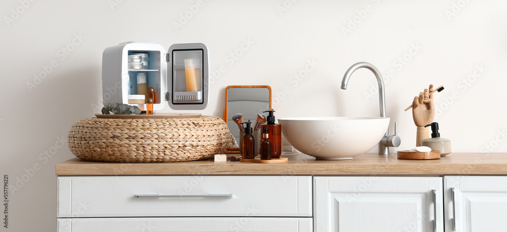 Obraz premium Open refrigerator with products, mirror and sink on stand near light wall in bathroom