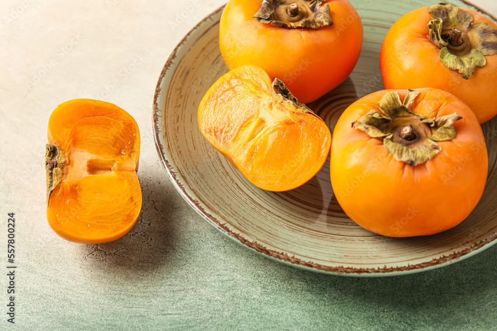 Plate with fresh persimmons on grunge background, closeup Plate with fresh persimmons on grunge background, closeup