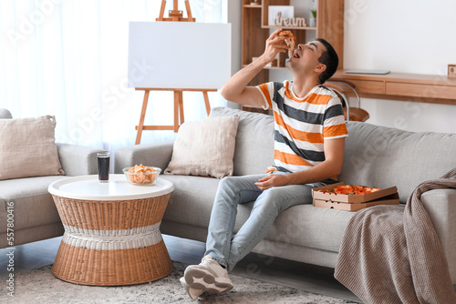 Young man eating tasty pizz...