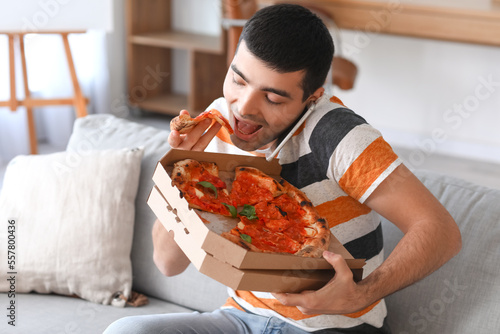 Young man eating tasty pizz...