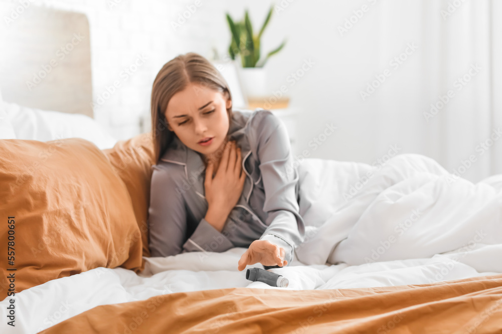 Sick young woman with inhaler in bed Sick young woman with inhaler in bed