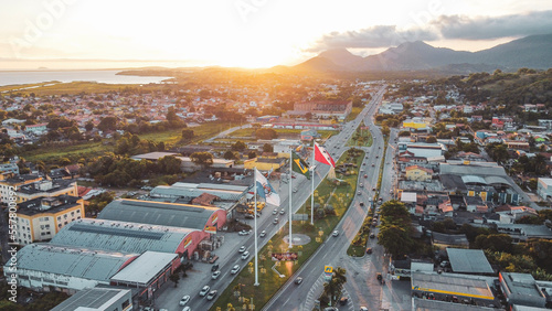 View of the city of Maricá, with the Amaral Peixoto highway that runs through the city. The flags of Maricá, the State of Rio de Janeiro and Brazil are present.