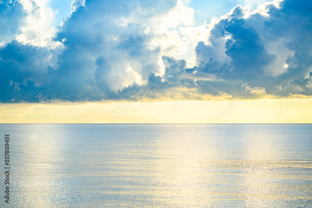 Obraz premium Sunset on tropical beach sea ocean with sunrise clouds. Banner for travel vacation. Scenery sky and reflection rays in water. Orange and golden sunset sky calmness tranquil sunlight summer mood.