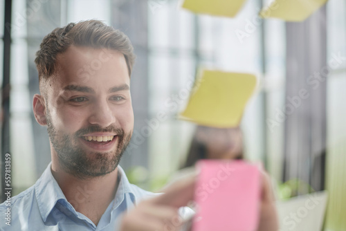 businessman is working on a project. Business man pointing at a note on the glass wall in the office.