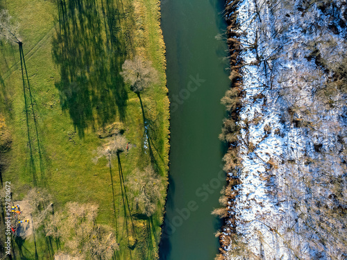 Obraz na płótnie Aerial view. The river as seen from above. Winter, spring. Half and half. Landscape, trees, snow, water, shadows. w salonie