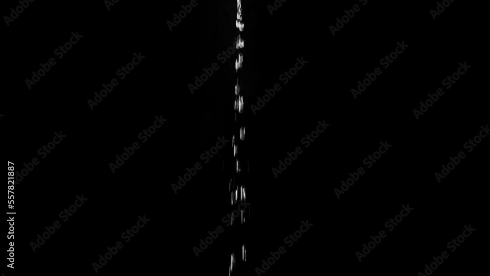 A thin jet of water from drops fall on a black background. Overlay template. A thin jet of water from drops fall on a black background. Overlay template.