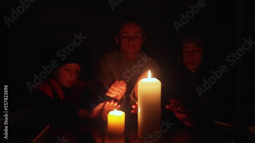 Family sitting around a table lit by candlelight during an electrical power cut.