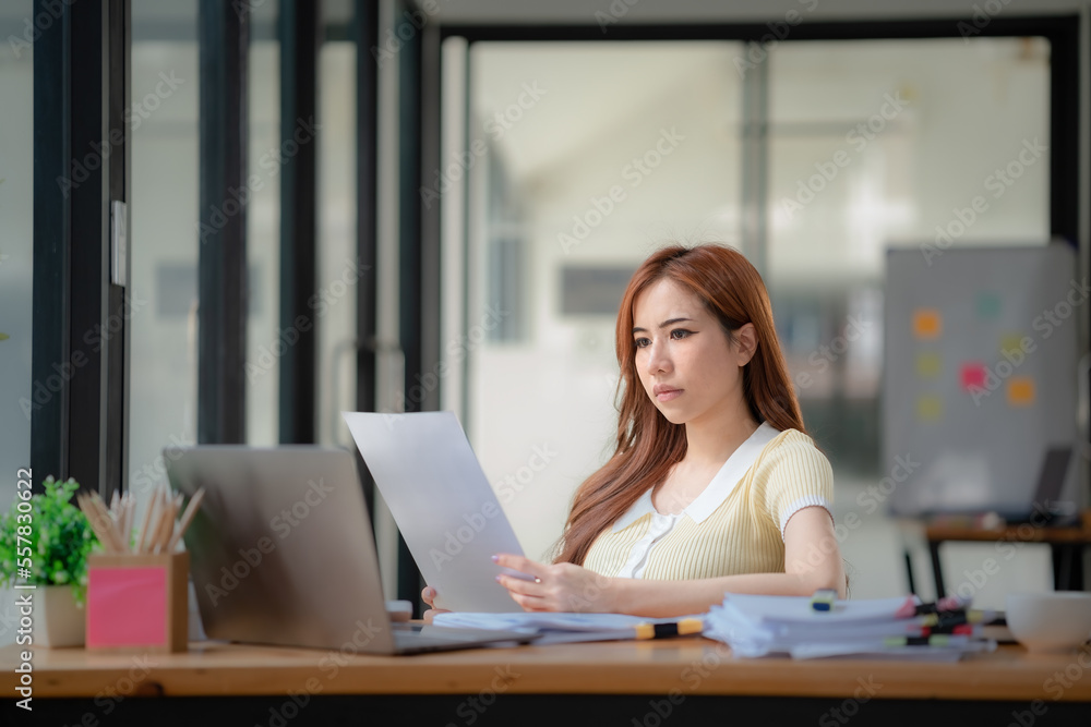 Stressed and serious Asian businesswoman or financial consultant reading a financial report. Stressed and serious Asian businesswoman or financial consultant reading a financial report.
