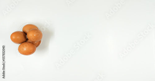 Top view of eggs in clear bowl on white background, isolated
