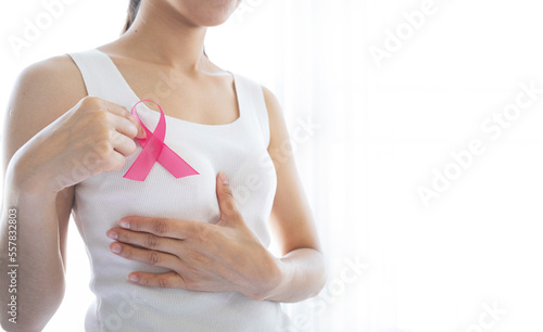 Fototapeta Naklejka Na Ścianę i Meble -  Pink ribbon on the chest of a woman in a white t-shirt. Symbol of breast cancer awareness campaign. Healthcare concept