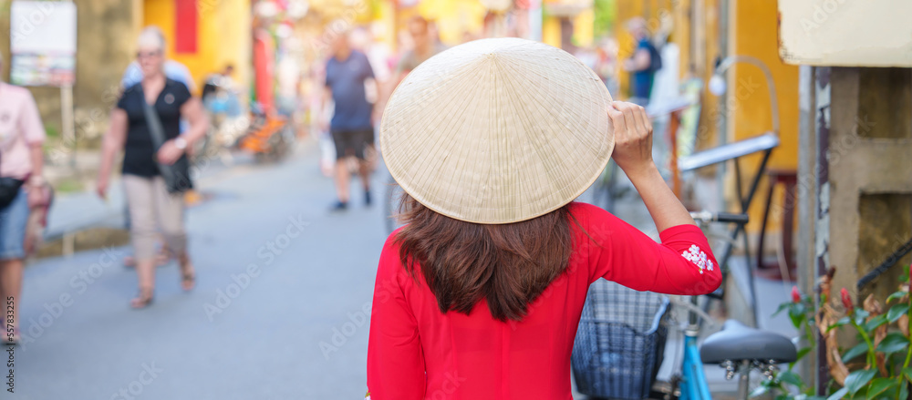 happy woman wearing Ao Dai Vietnamese dress, asian traveler sightseeing at Hoi An ancient town in central Vietnam. landmark and popular for tourist attractions. Vietnam and Southeast travel concept