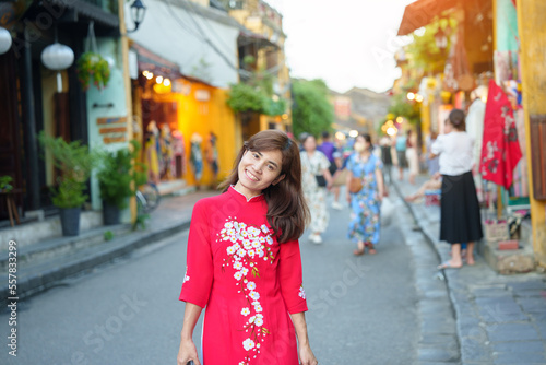 happy woman wearing Ao Dai Vietnamese dress, asian traveler sightseeing at Hoi An ancient town in central Vietnam. landmark and popular for tourist attractions. Vietnam and Southeast travel concept