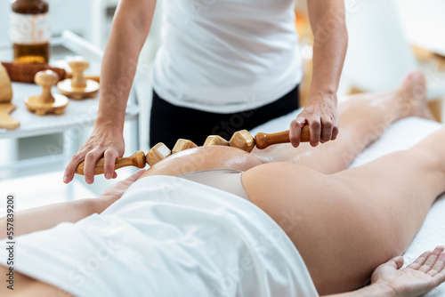 Therapist woman doing back massage with wooden balls to a pretty woman on the spa center