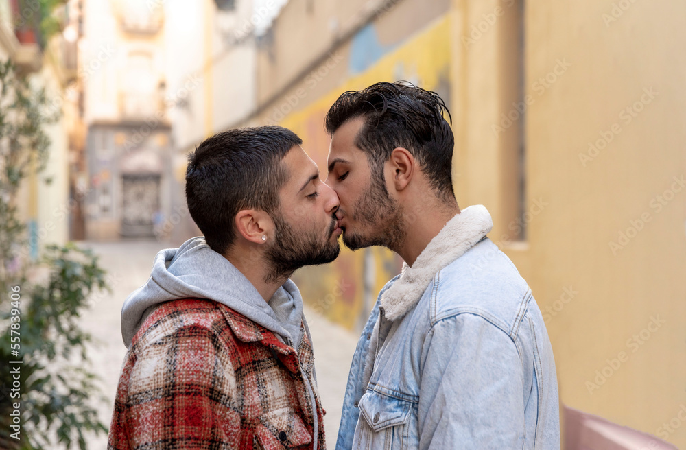 Romantic moment of a young gay couple kissing on the street