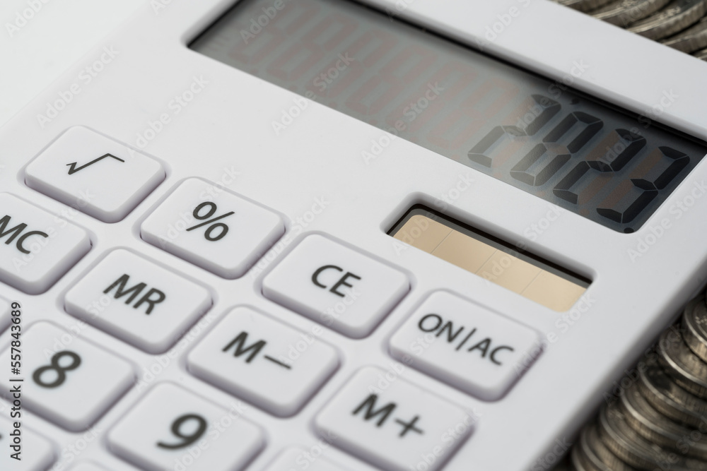 A white calculator with 2023 on the screen. A concept for recording income, expenses and controlling finances.