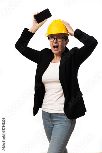 mujer gesticulando trabajando con traje y casco amarillo usando tecnología como Tablet y móvil sobre fondo blanco