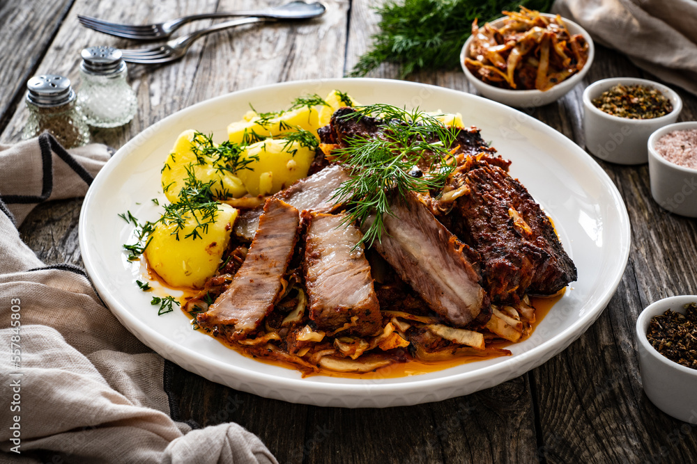 Tasty roast ribs with boiled potatoes on wooden table
Tasty roast ribs with boiled potatoes on wooden table