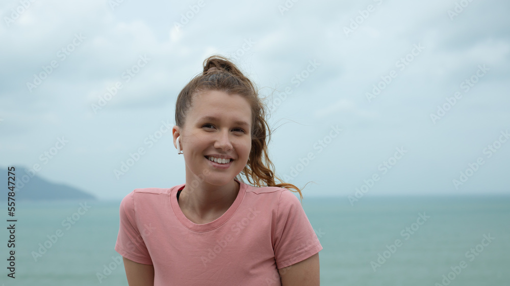 portrait of a beautiful girl in earphones on the natural background of ocean or sea in the mountain, young woman smile, listen to music and relaxes in fresh air and breathe deep, deeply at summer day portrait of a beautiful girl in earphones on the natural background of ocean or sea in the mountain, young woman smile, listen to music and relaxes in fresh air and breathe deep, deeply at summer day