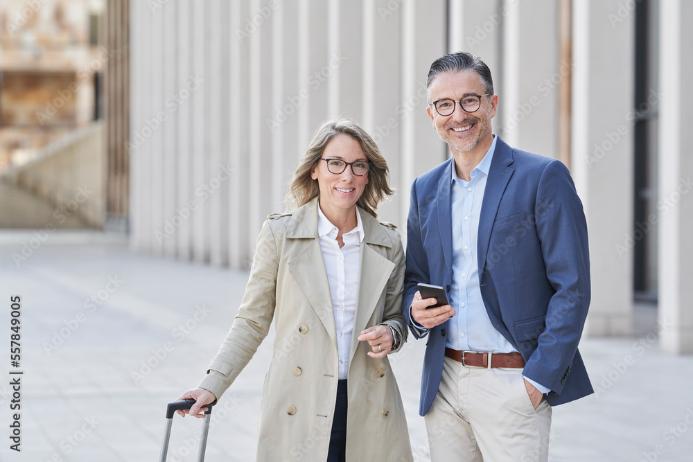 Business colleagues with suitcase standing on footpath Business colleagues with suitcase standing on footpath