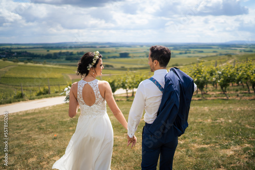Wedding couple, groom is running while holding brides hand  in the vineyards of Rheinhessen © Tobias