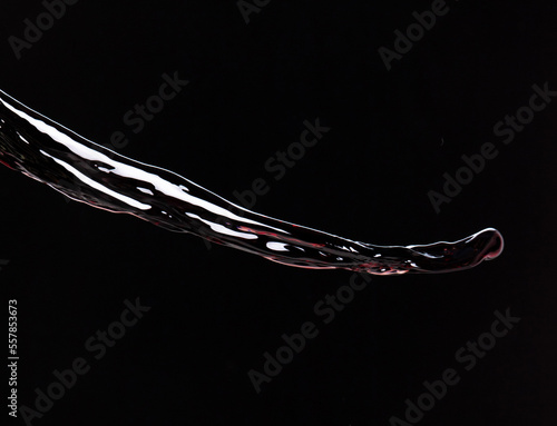 Flow of Crude Oil gasoline pour down over dark background isolated. Black water liquid fall down line. Black Ink, Coffee drink pour splash drop as gold crude oil or sticky water