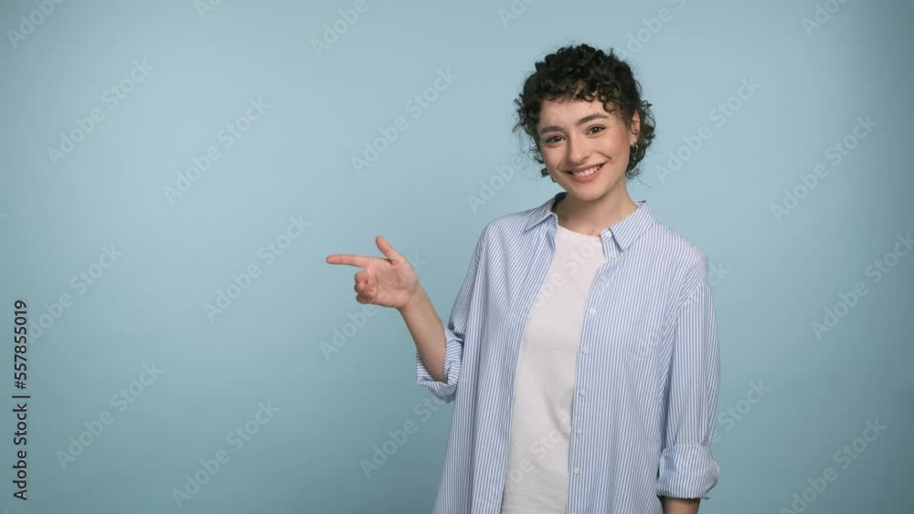 Surprised excited woman in blue shirt pointing index finger aside up showing direction or way. Isolated on blue background studio Surprised excited woman in blue shirt pointing index finger aside up showing direction or way. Isolated on blue background studio