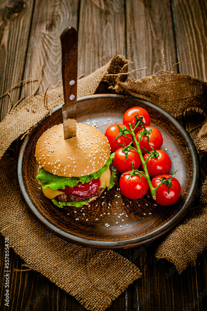 Appetite homemade classic beef burger on rustic wooden serving table with knife. Homemade cooking 