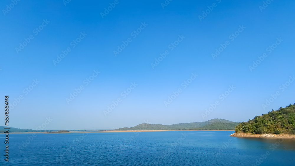 Blue River with clear blue sky and green forest background, summer scene