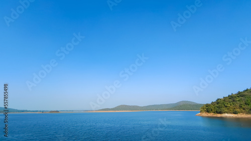 Blue River with clear blue sky and green forest background, summer scene