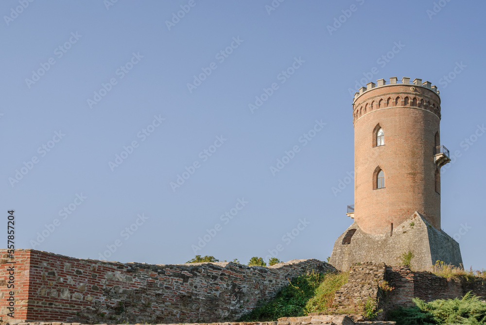 Medieval old brick tower of castle. Medieval building. Tower of ancient castle with opened windows. Historic architectural element on blue sky background Medieval old brick tower of castle. Medieval building. Tower of ancient castle with opened windows. Historic architectural element on blue sky background