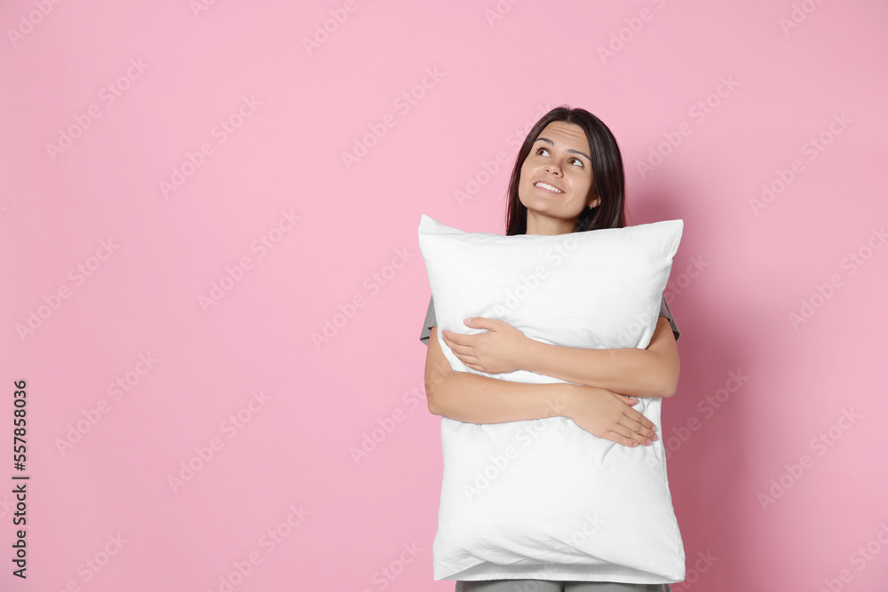 Happy young woman hugging soft pillow on pink background, space for text Happy young woman hugging soft pillow on pink background, space for text