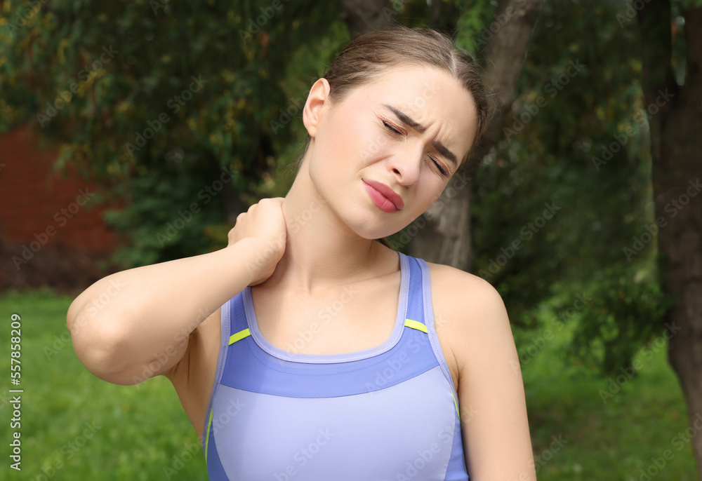 Young woman suffering from neck pain outdoors Young woman suffering from neck pain outdoors